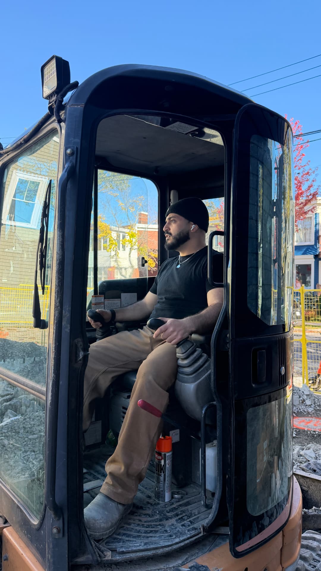 Crew member at the controls of the compact excavator on a stonework job