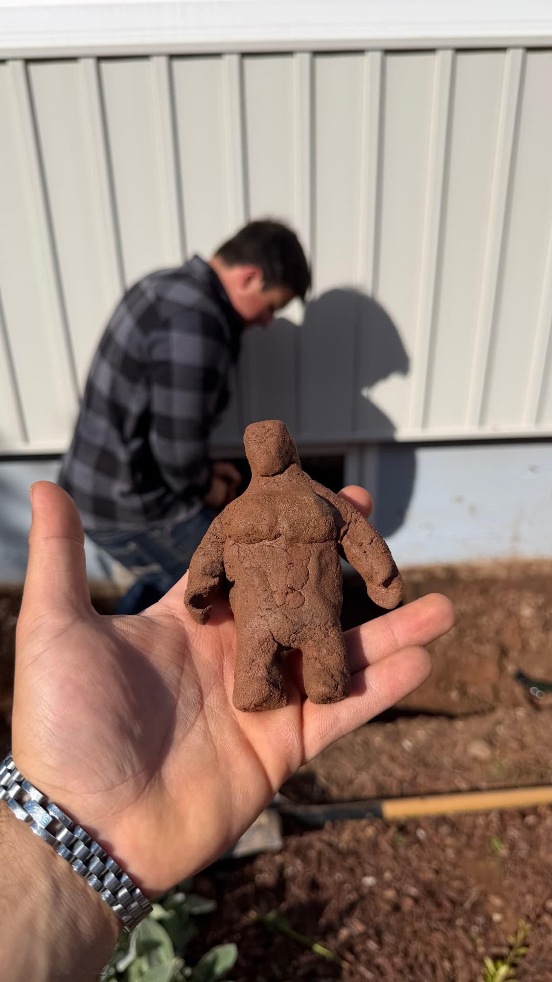 Crew member with a playful dirt sculpture during a garden-bed job