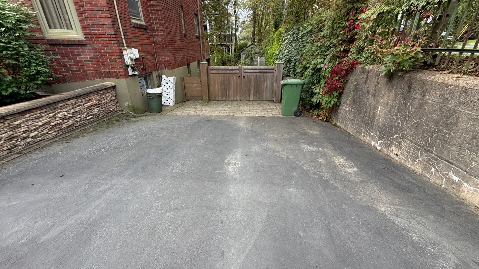 Cleared residential driveway beside garden beds and a retaining wall
