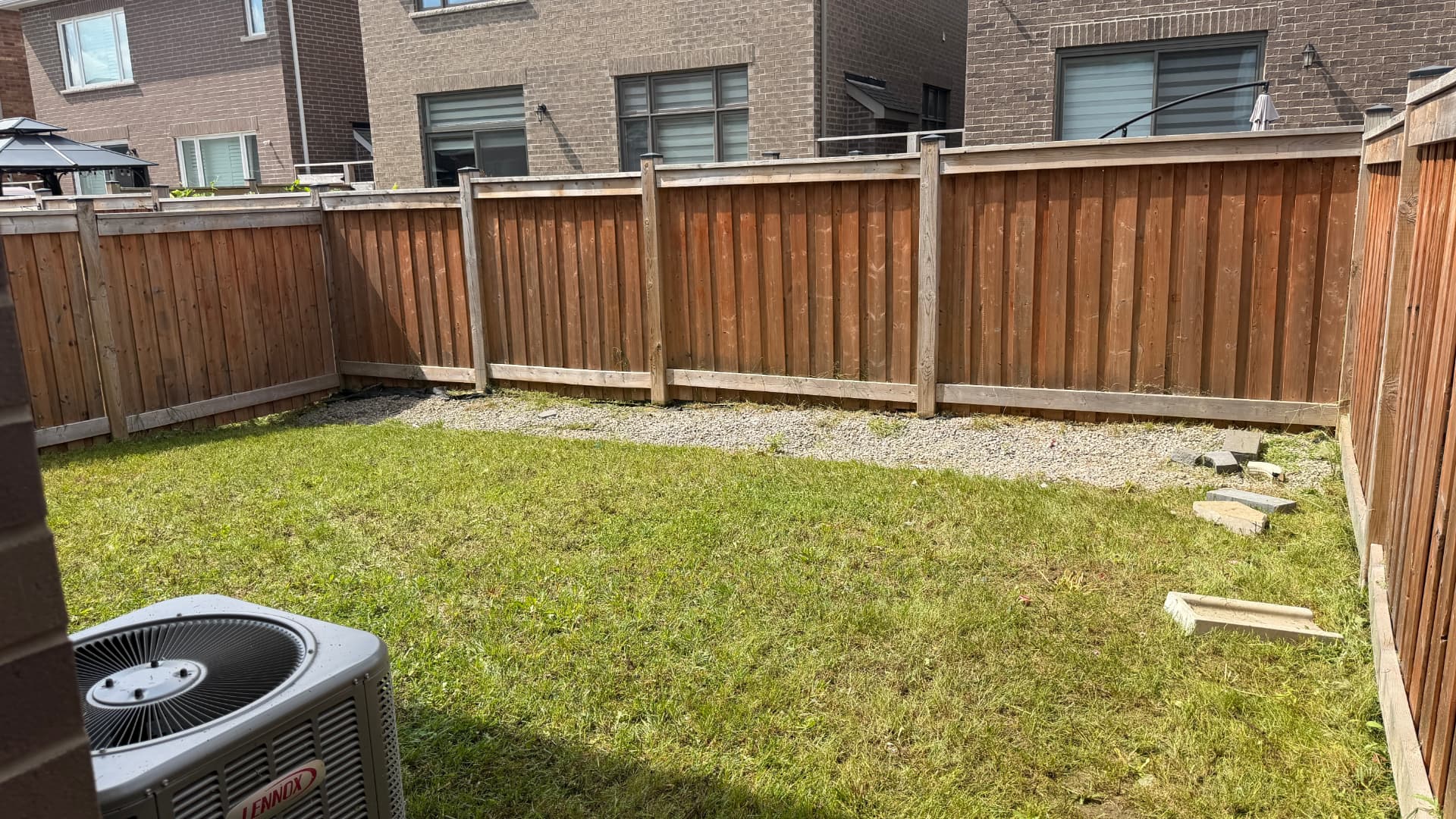 Backyard lawn cut clean to the fence line and gravel border