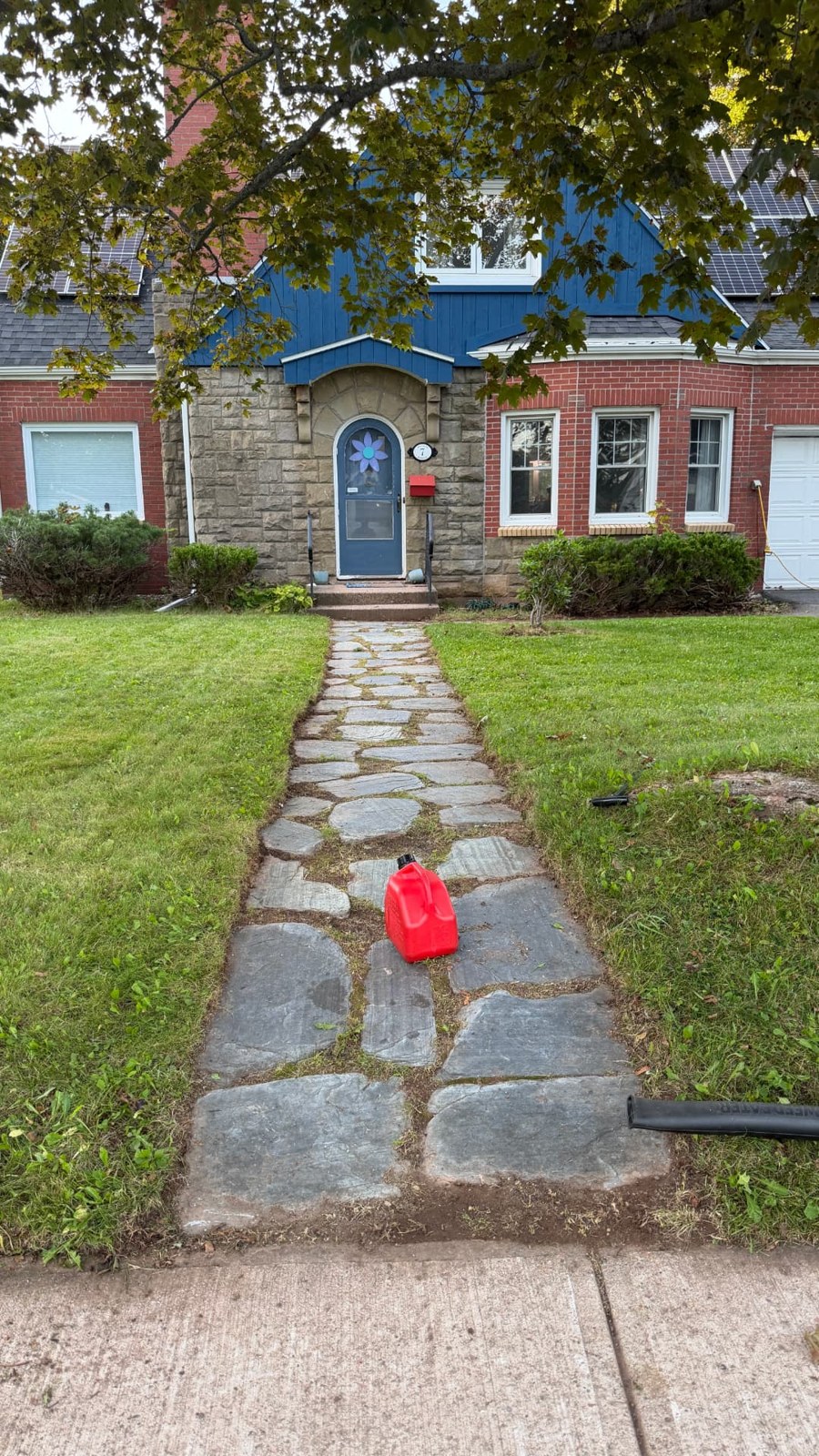 Stone front walkway bordered by a maintained lawn and trimmed shrubs