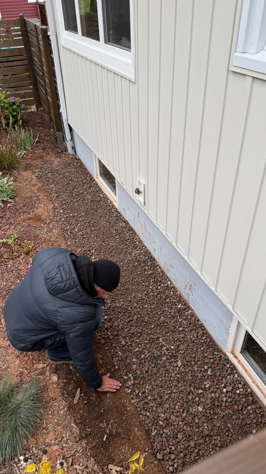 Topping up stone along a home's foundation during a yard refresh